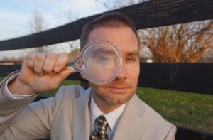A Man in a Suit Looking at a Magnifying Glass