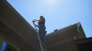 A Man Standing on a Ladder for Roof Inspection