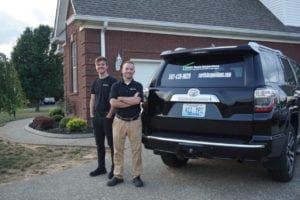 Two Men Standing Behind a Black Color Car