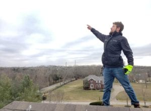 A Man Pointing at a Blue Sky From the Roof